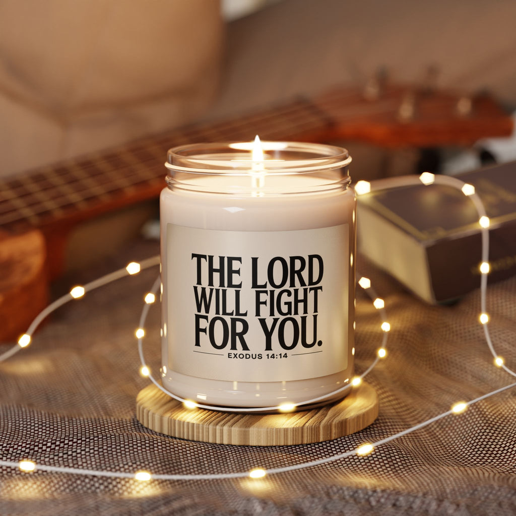 Candle in a jar with 'The Lord Will Fight For You' text on a wooden coaster with fairy lights and a guitar in the background.