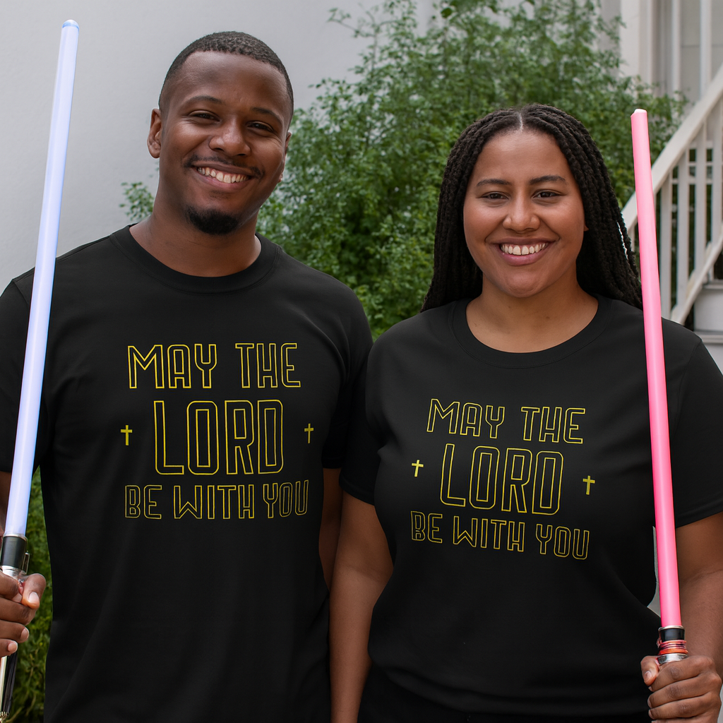 Two people wearing black t-shirts with 'May the Lord be with you' text, holding lightsabers.