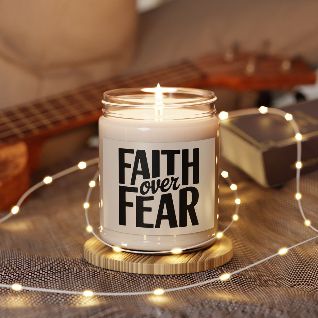 Candle in a jar with 'Faith Over Fear' text on a wooden coaster surrounded by string lights and a guitar in the background.