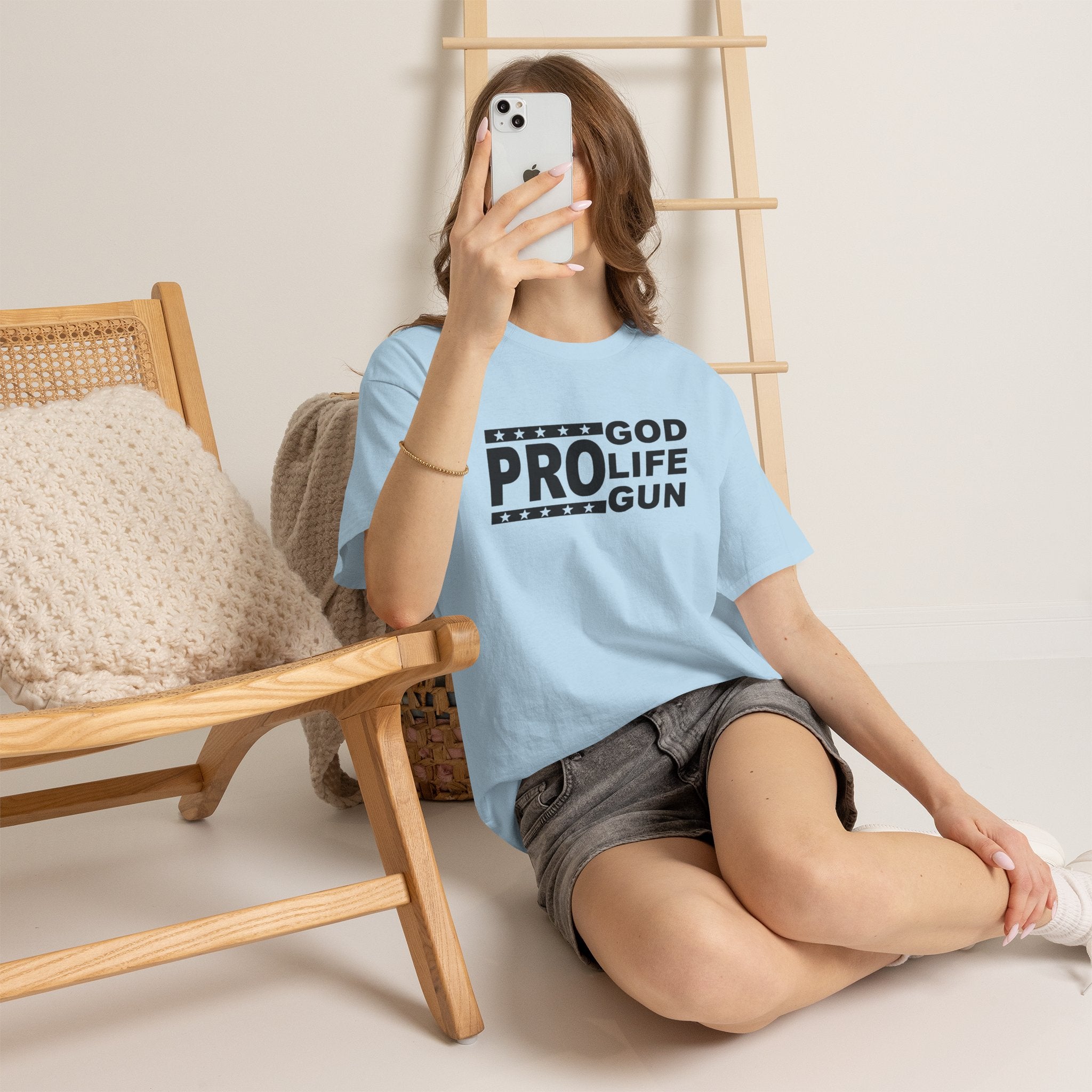 Person wearing a light blue t-shirt with 'GOD PRO LIFE GUN' text, sitting on the floor.