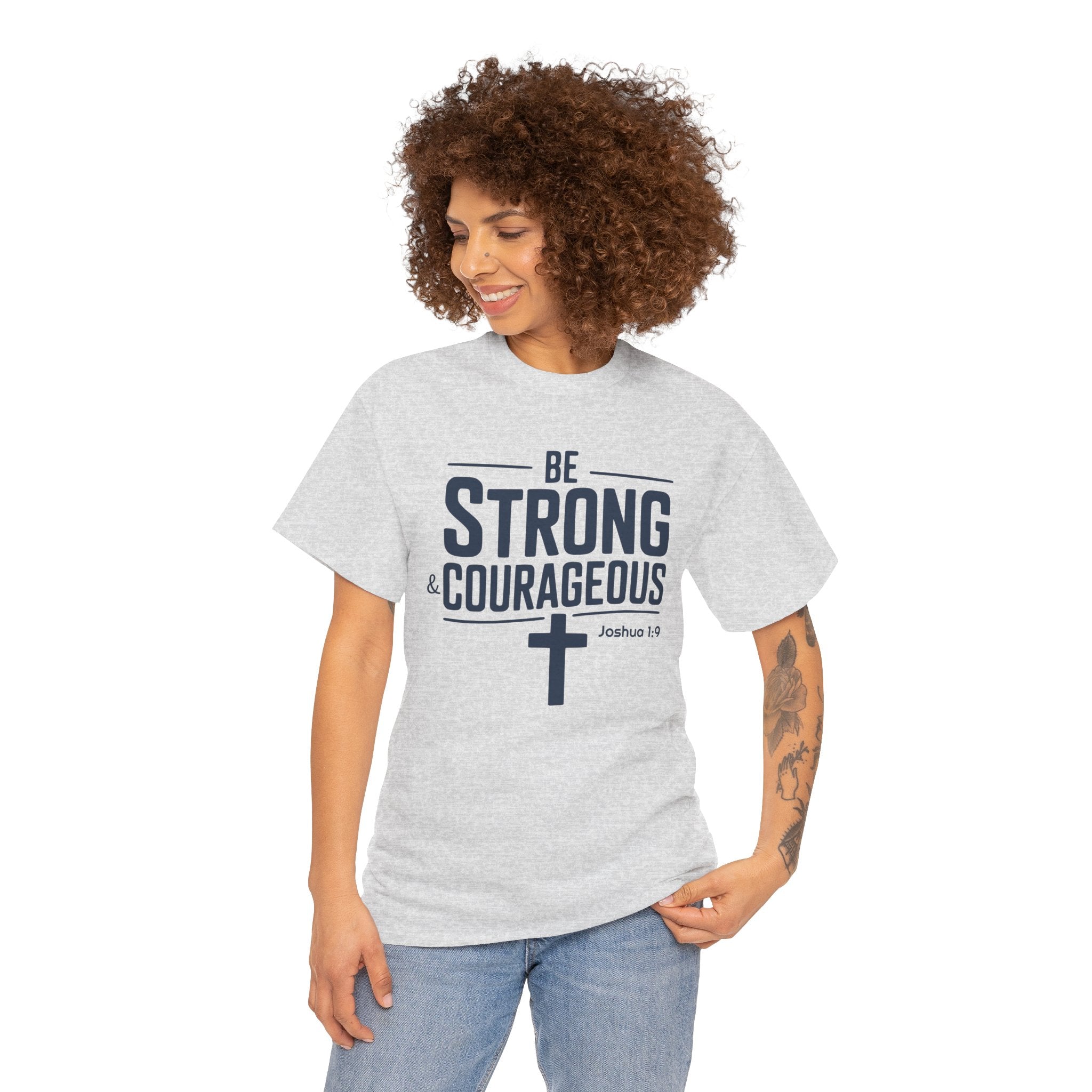 Woman wearing a gray t-shirt with 'Be Strong & Courageous' text and cross design on a white background