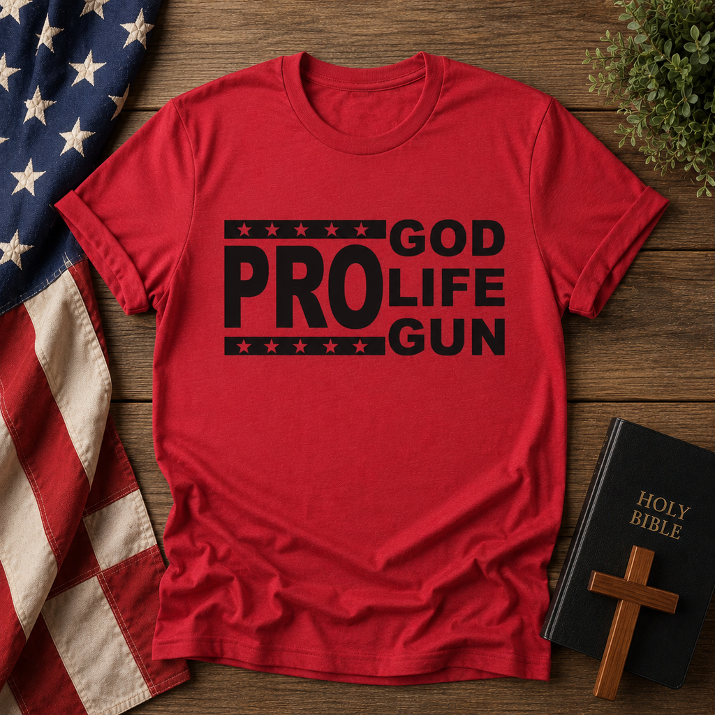Red t-shirt with 'GOD PRO LIFE GUN' text on a wooden surface with American flag, Bible, and cross.